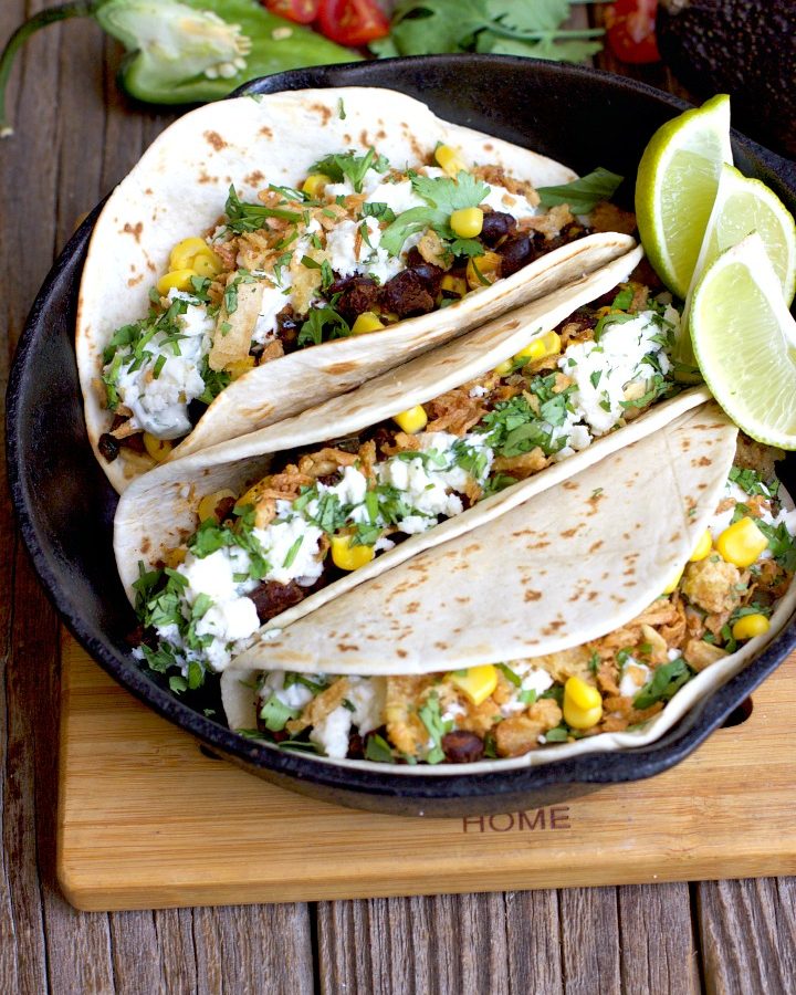 Black Bean & Corn Soft Tacos in a cast iron pan on a wooden surface.