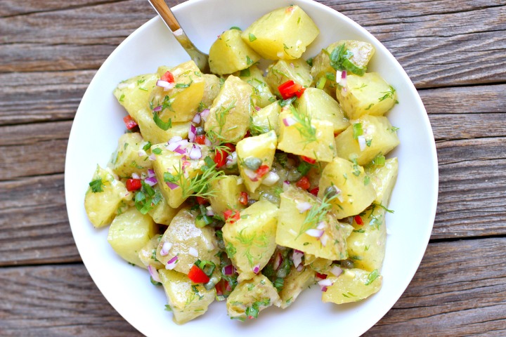Dijon Potato Salad in a white bowl with a fork on a rustic wooden surface