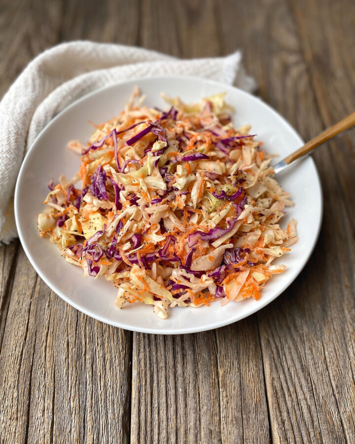 White bowl of coleslaw on a rustic surface