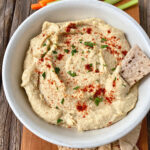 white bowl with oil-free hummus, veg sticks and pita bread